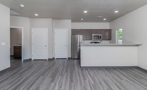 an empty living room and kitchen with a counter top and a refrigerator