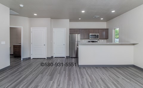 A kitchen with a refrigerator, microwave, and cabinets.