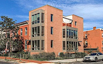 A red brick building with a white car parked in front.