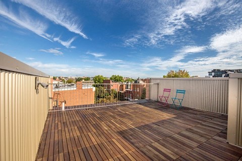 A wooden deck with two chairs and a table on a rooftop.