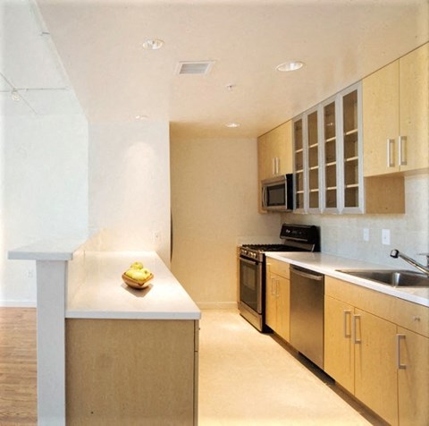 A kitchen with a white counter top and stainless steel appliances.