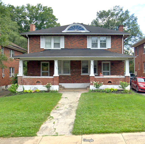 A red brick house with a white front porch.