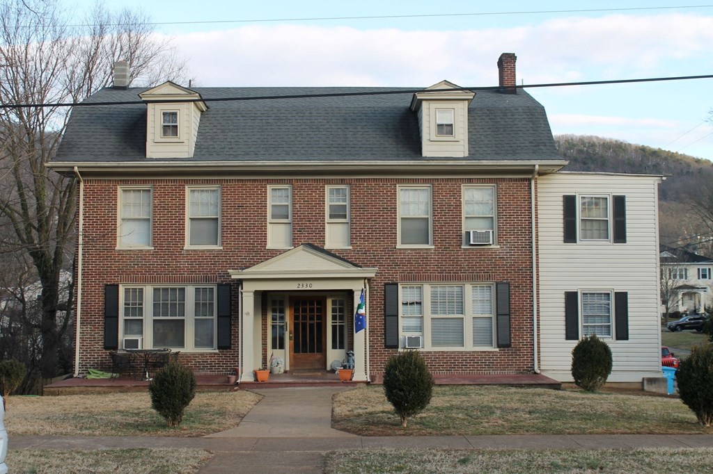 a red brick house with white siding and a black roof
