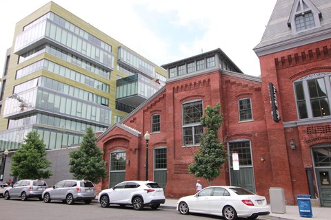 A white car is parked in front of a red brick building.