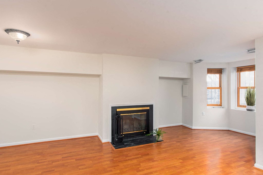an empty living room with a fireplace and wooden floors