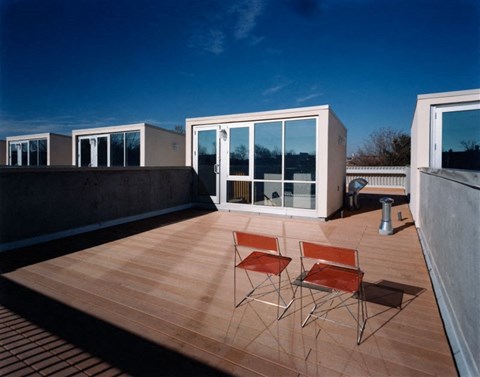 a roof terrace with two chairs and a glass door