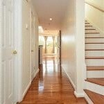 the hallway of a house with stairs and a wooden floor