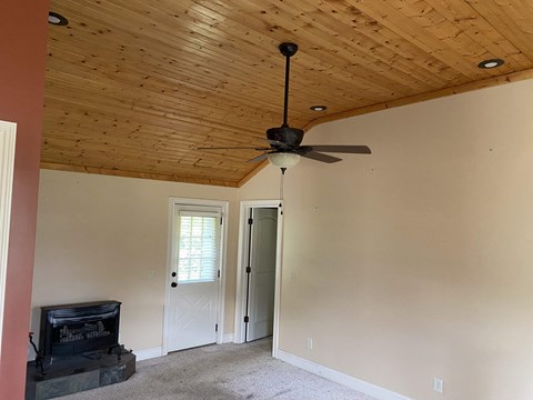 a living room with a ceiling fan and a door to a closet