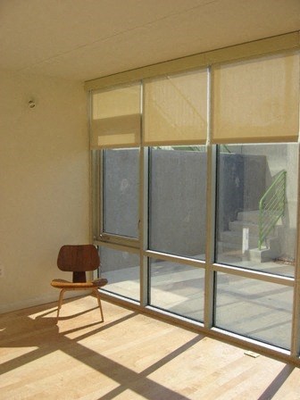 A chair is in front of a window with blinds.