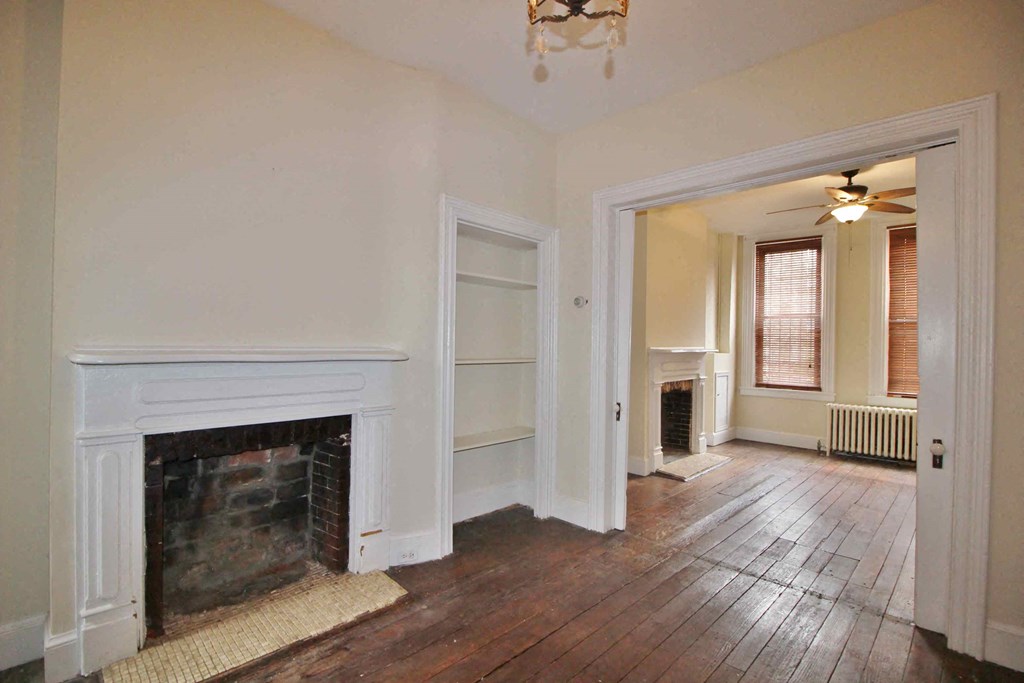 A room with a fireplace and wooden floors.