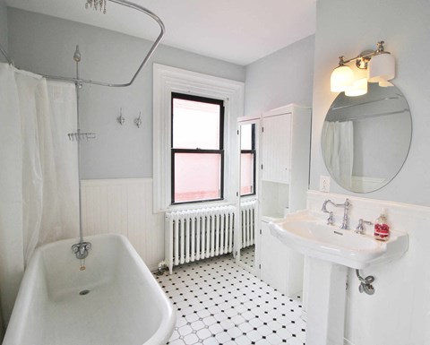 A white bathroom with a black and white floor.