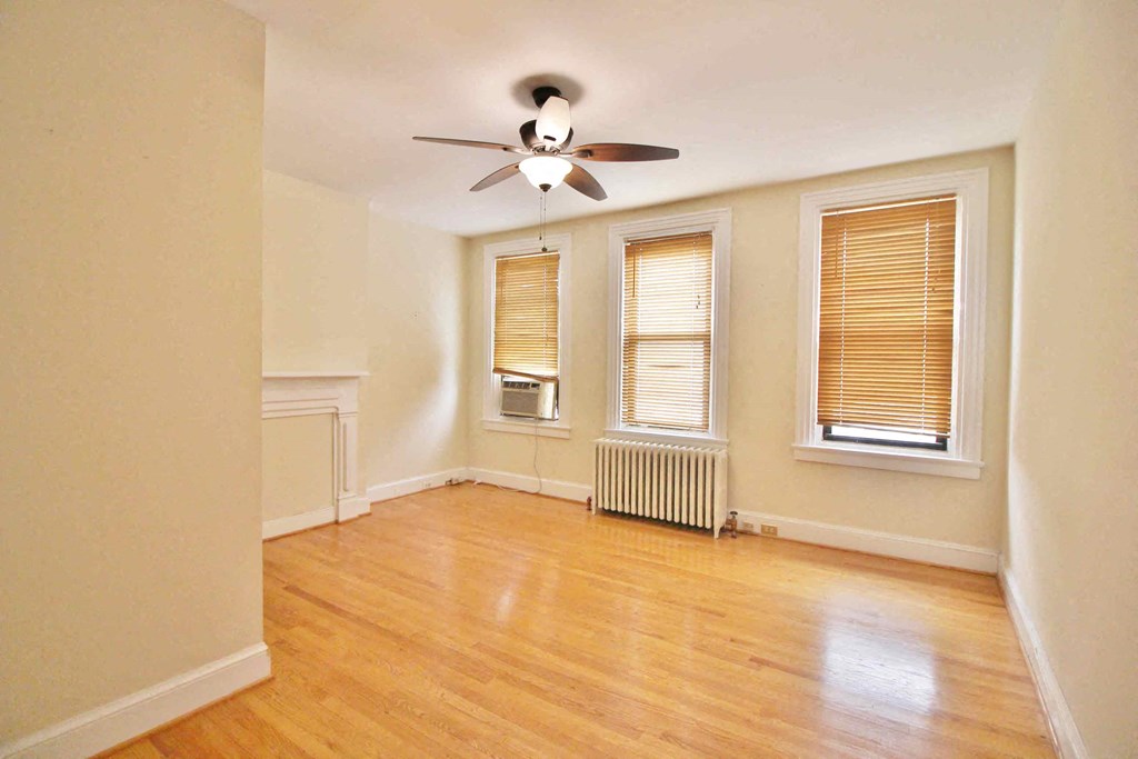 A room with a ceiling fan and a window with blinds.