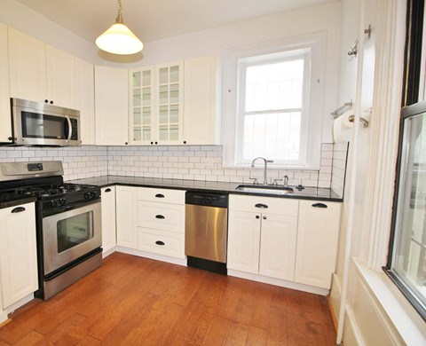 A kitchen with white cabinets and a black stove top oven.