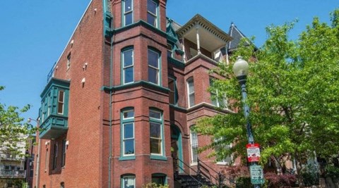 A red brick building with green trim and a street lamp in front.