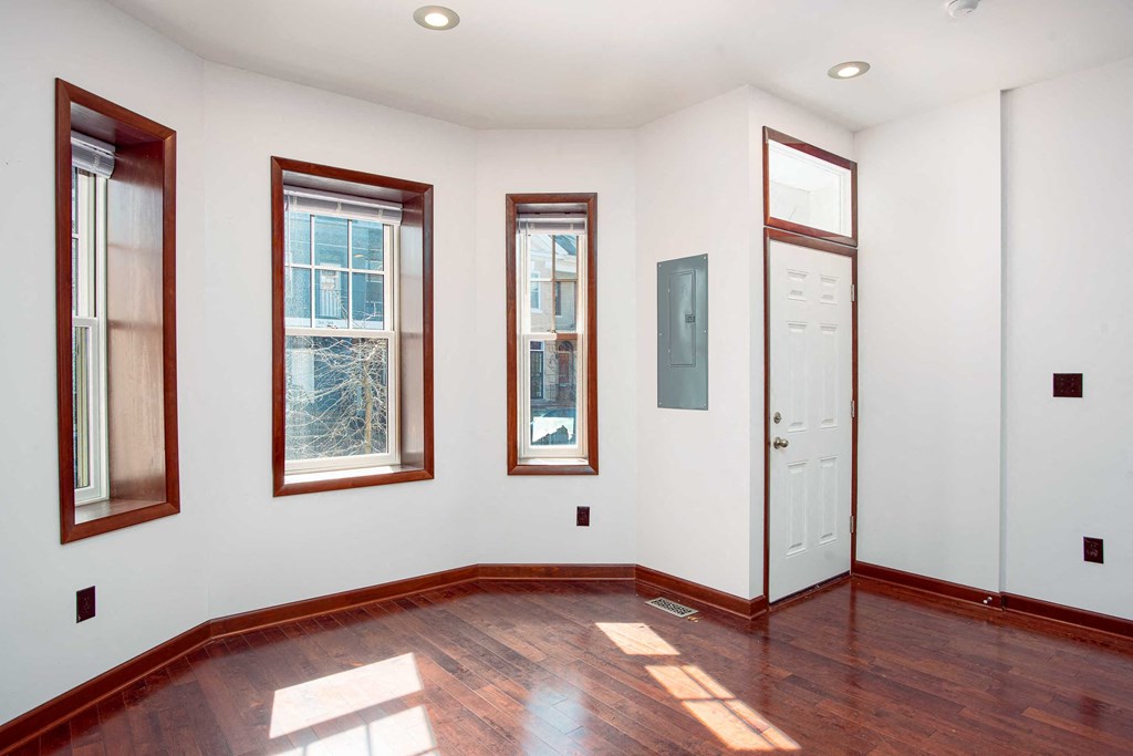 a room with wood floors and three windows and a white door