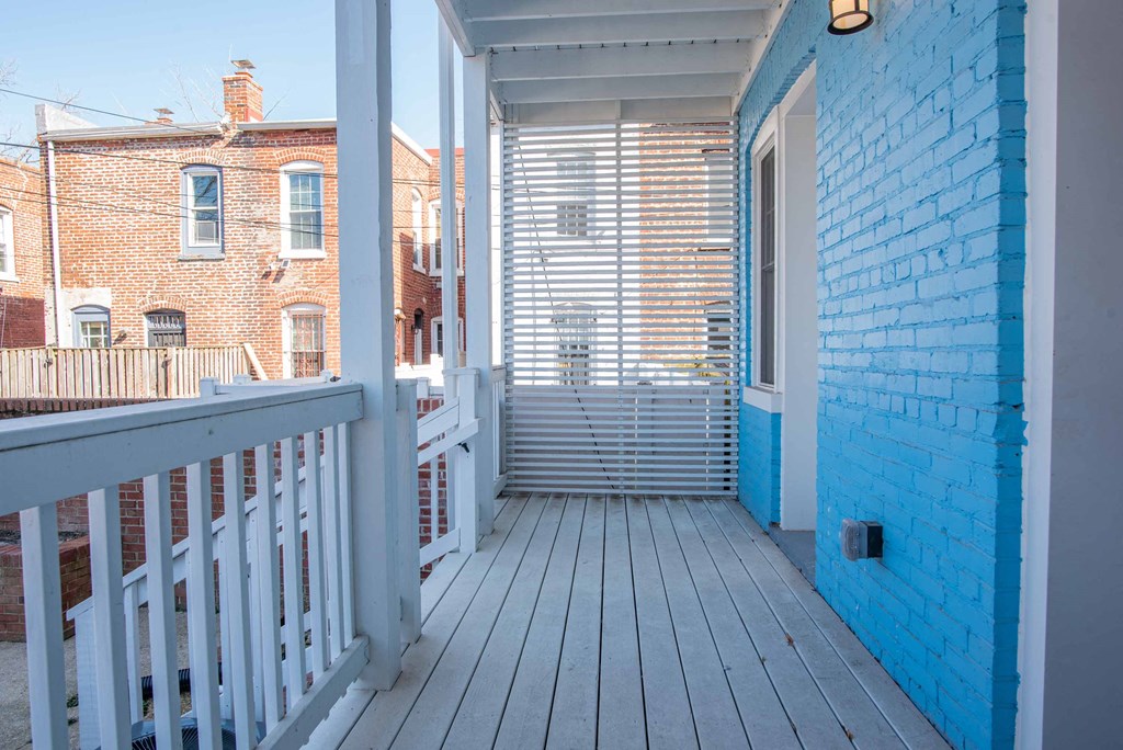 a balcony with a white deck and a blue brick wall