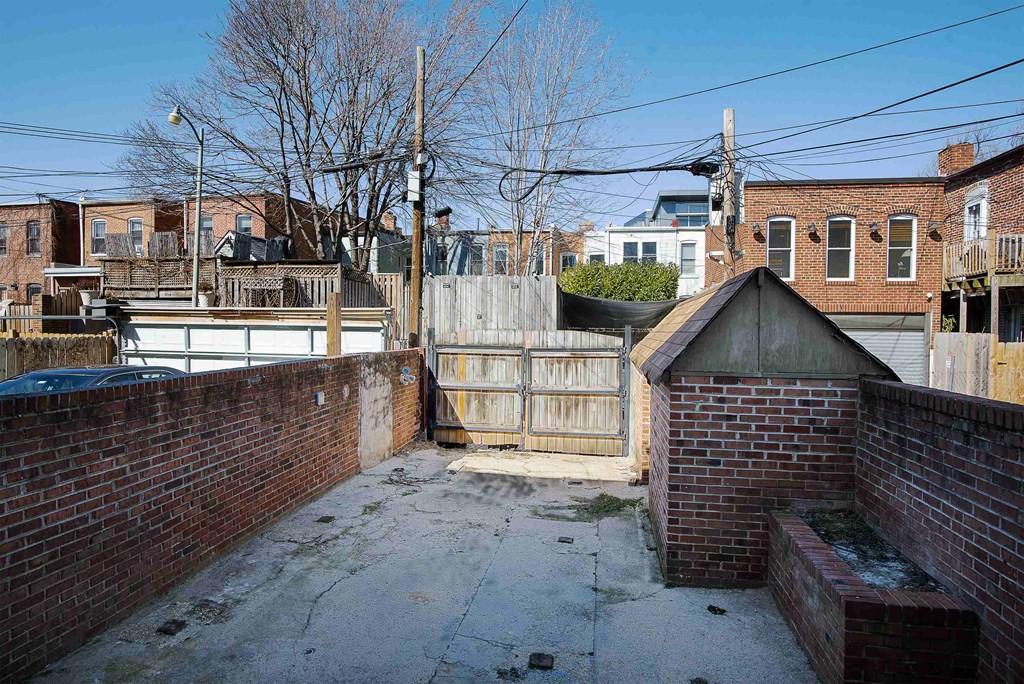 a back yard with a fence and a brick wall and a wooden fence
