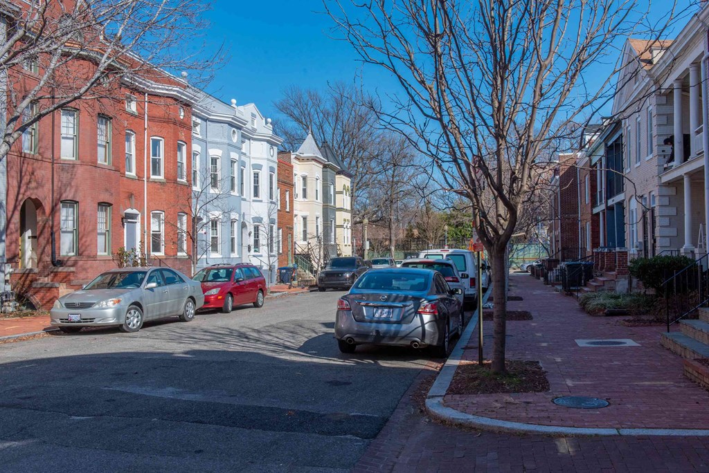 a city street with cars parked in front of houses