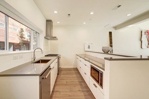 a large white kitchen with stainless steel appliances and a large window