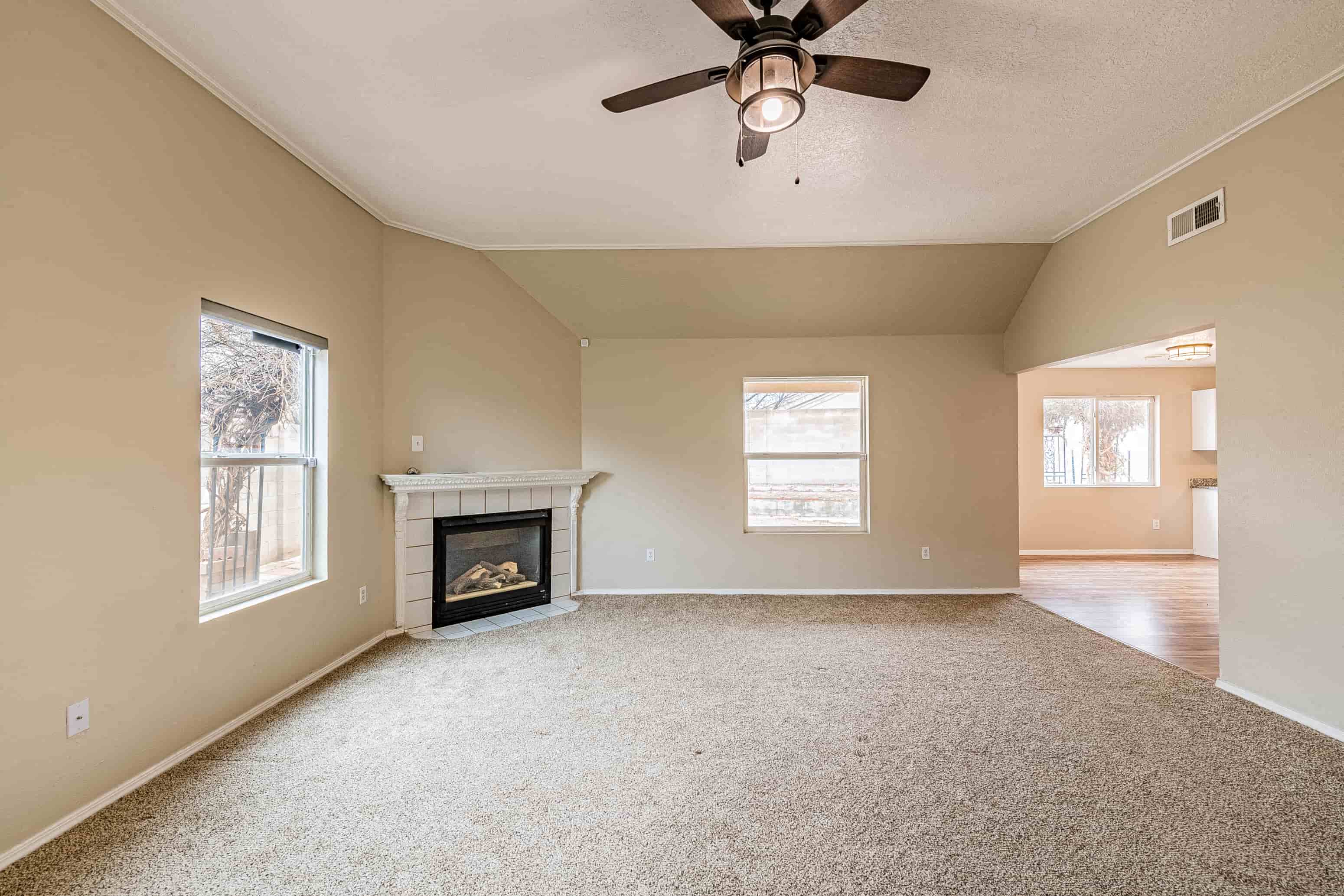 an empty living room with a fireplace and a ceiling fan