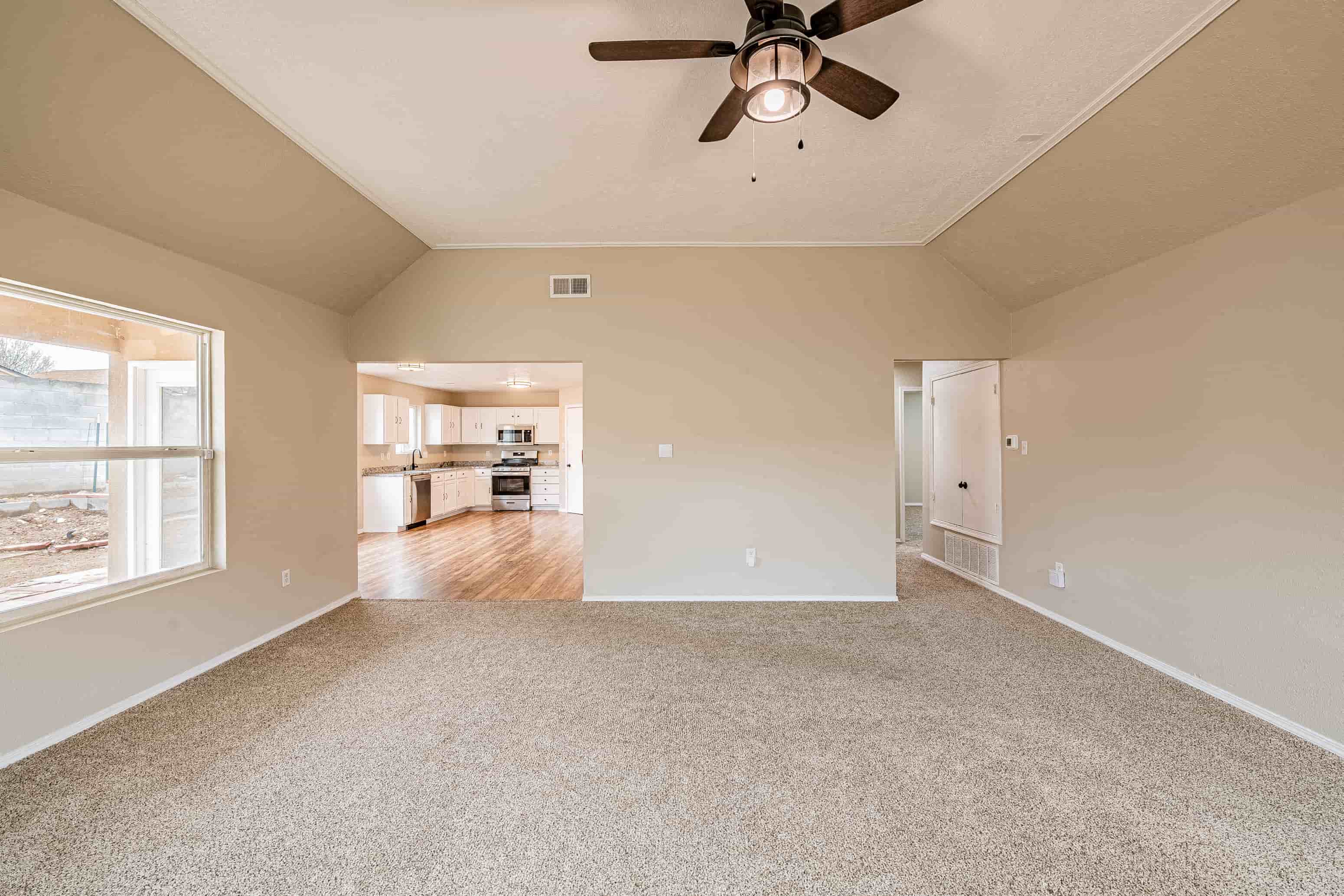 an empty living room with a ceiling fan