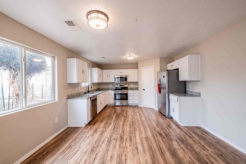 an empty kitchen with white cabinets and a large window