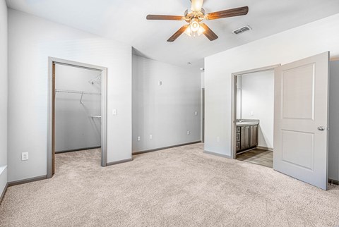 A spacious room with a ceiling fan and carpeted floor.