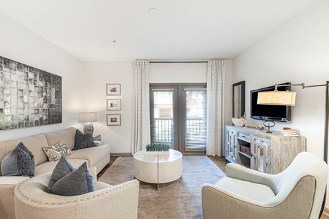 A living room with a white couch and a television on a wooden stand.
