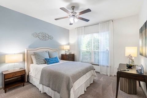 A bedroom with a large bed and a ceiling fan.