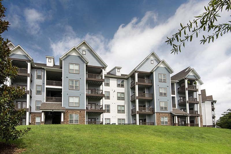 an apartment building on top of a green hill