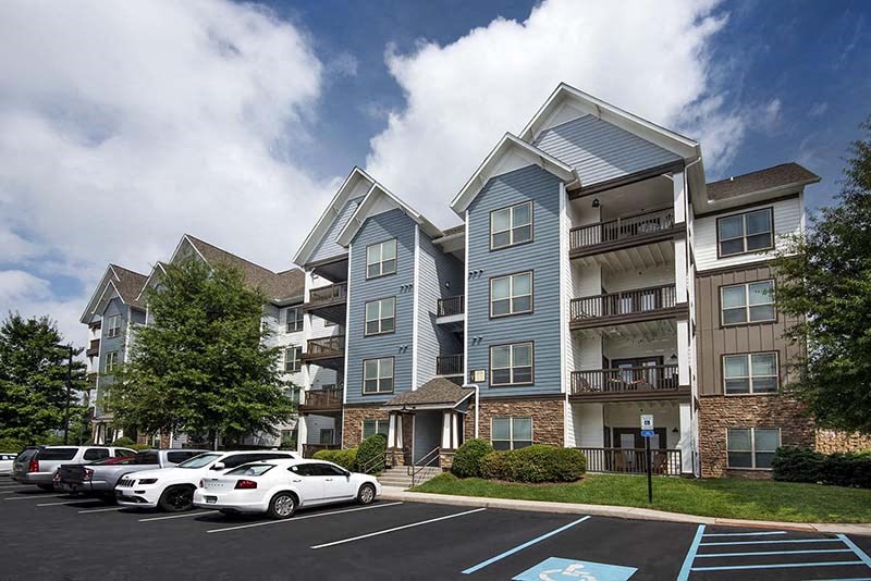 an apartment building with cars parked in a parking lot