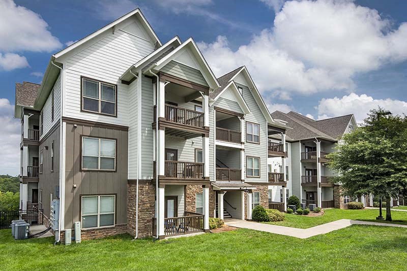 a row of apartment buildings with grass and trees