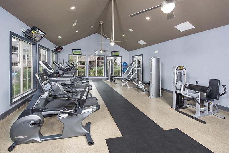 a gym with weights and cardio equipment and windows