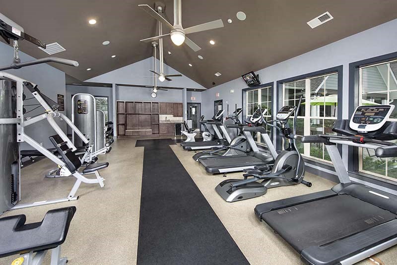 a gym with a lot of exercise equipment and windows