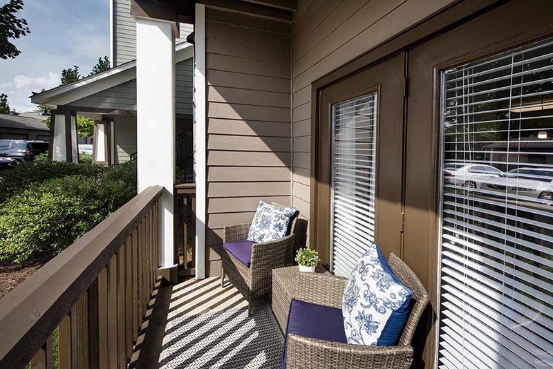 a porch with two wicker chairs and a door