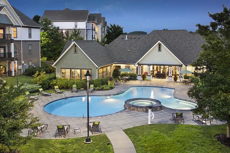 a swimming pool with chairs around it in front of a house