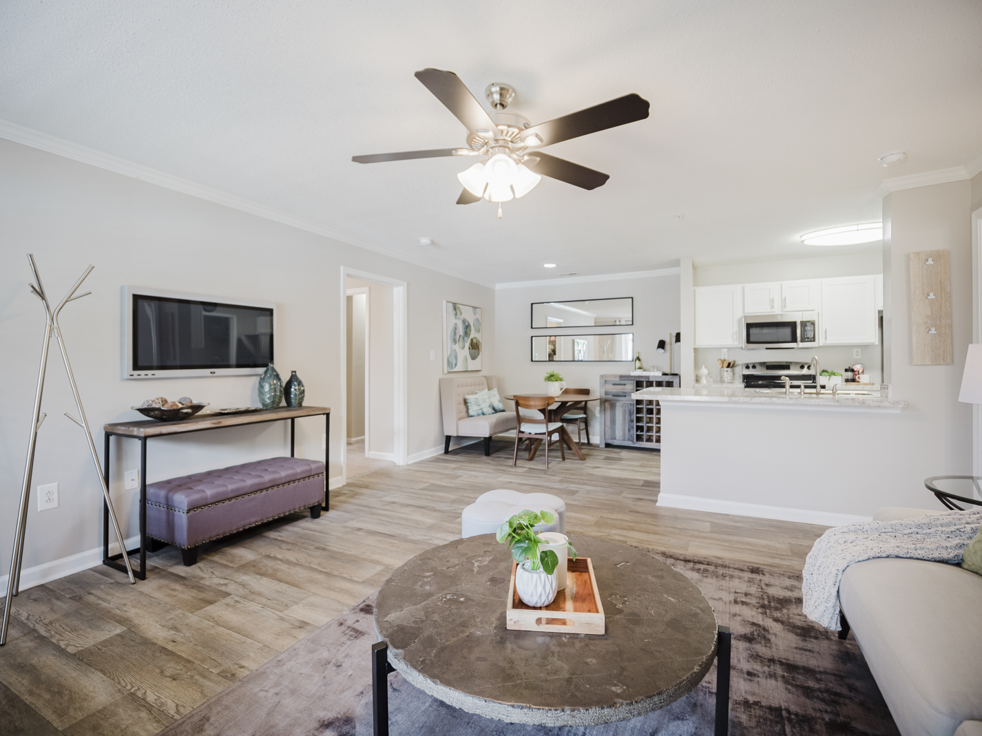 A living room with a brown coffee table and a flat screen TV mounted on the wall.