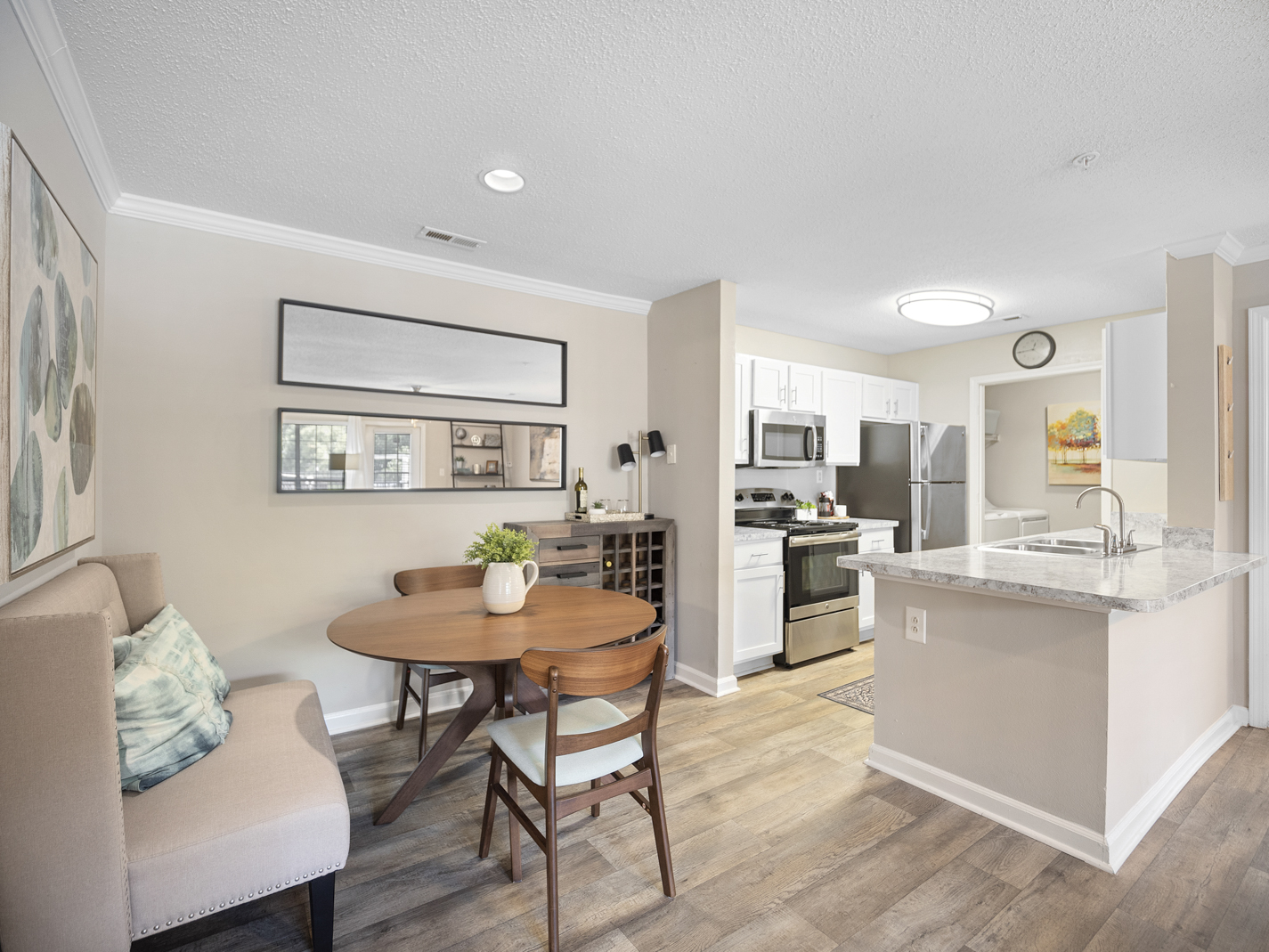 A modern kitchen with a dining table and chairs in the foreground and a kitchen island in the background.
