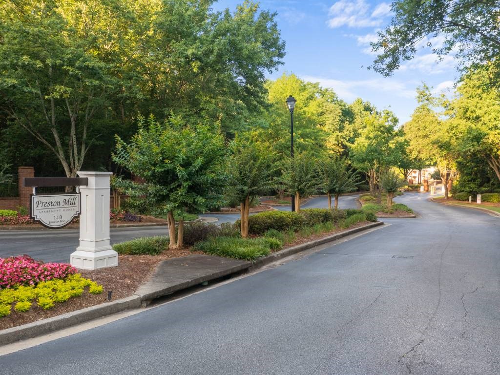 a street with a sign and trees on the side of a road