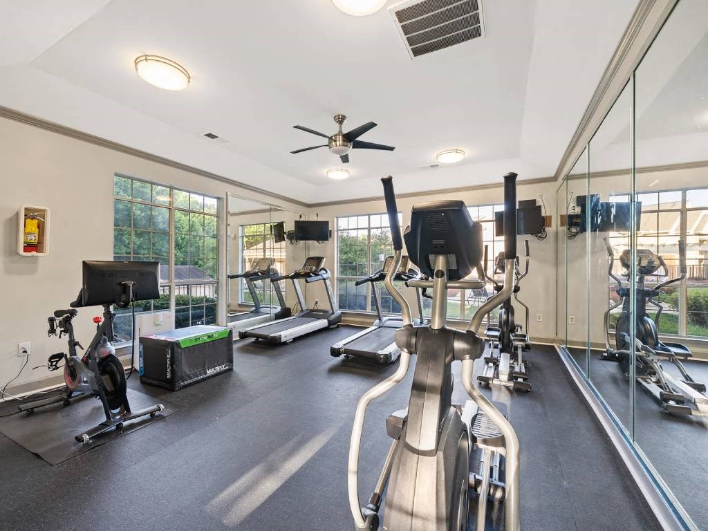the gym is equipped with cardio equipment and glass windows