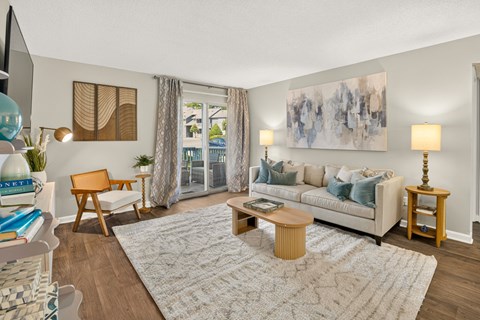 A living room with a white couch, a wooden chair, a coffee table, and a painting on the wall.