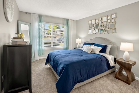 A bedroom with a blue bedspread and a wooden side table.