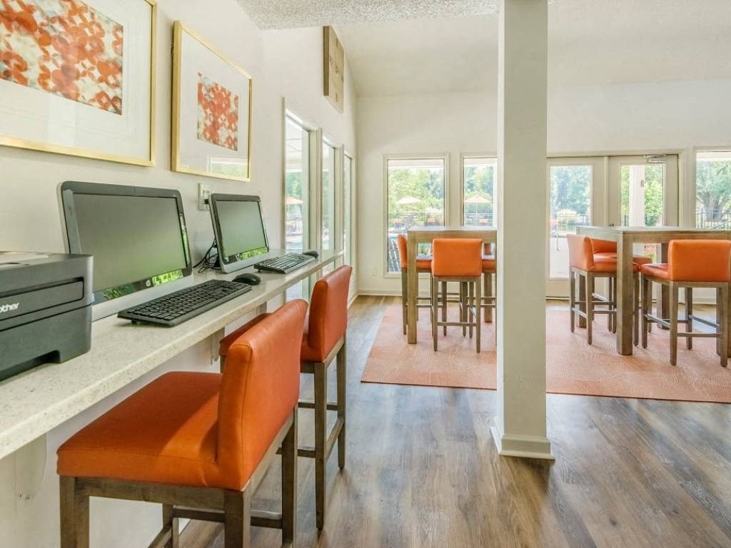 a living room with a computer desk and chairs