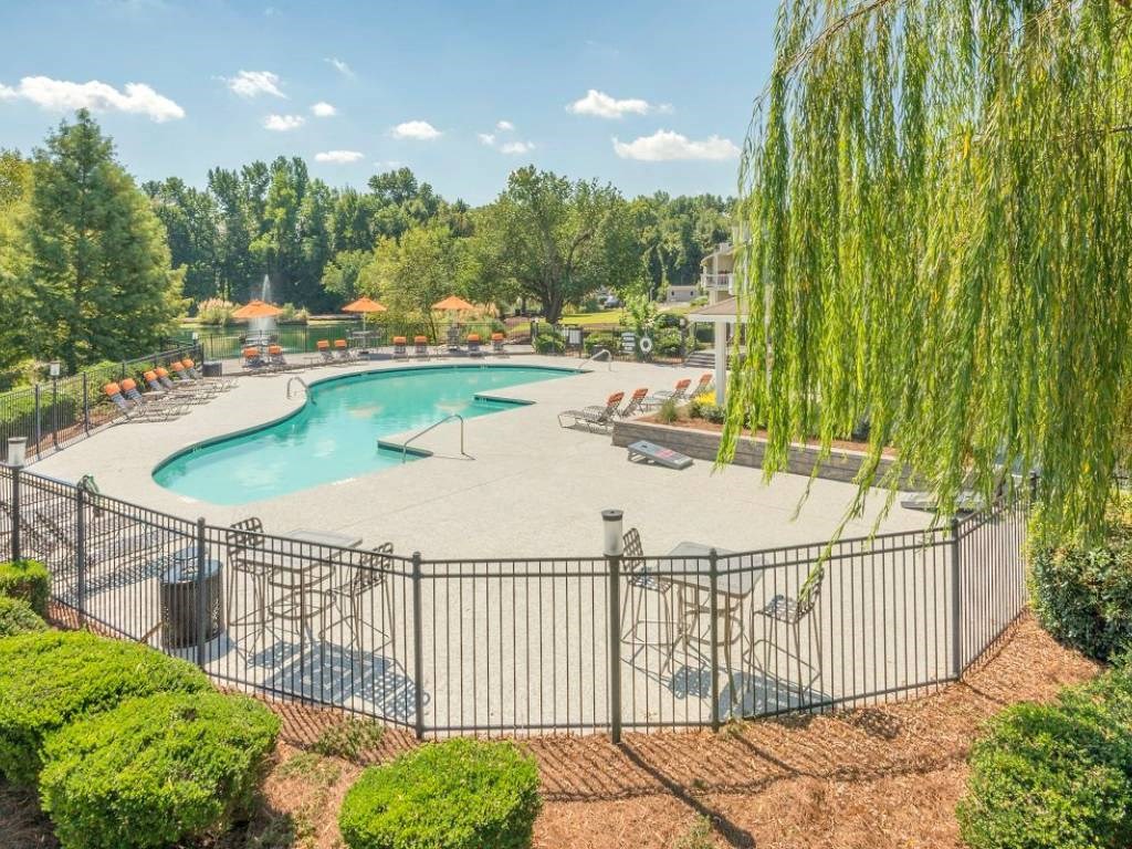 a view of a pool with a fence and chairs around it