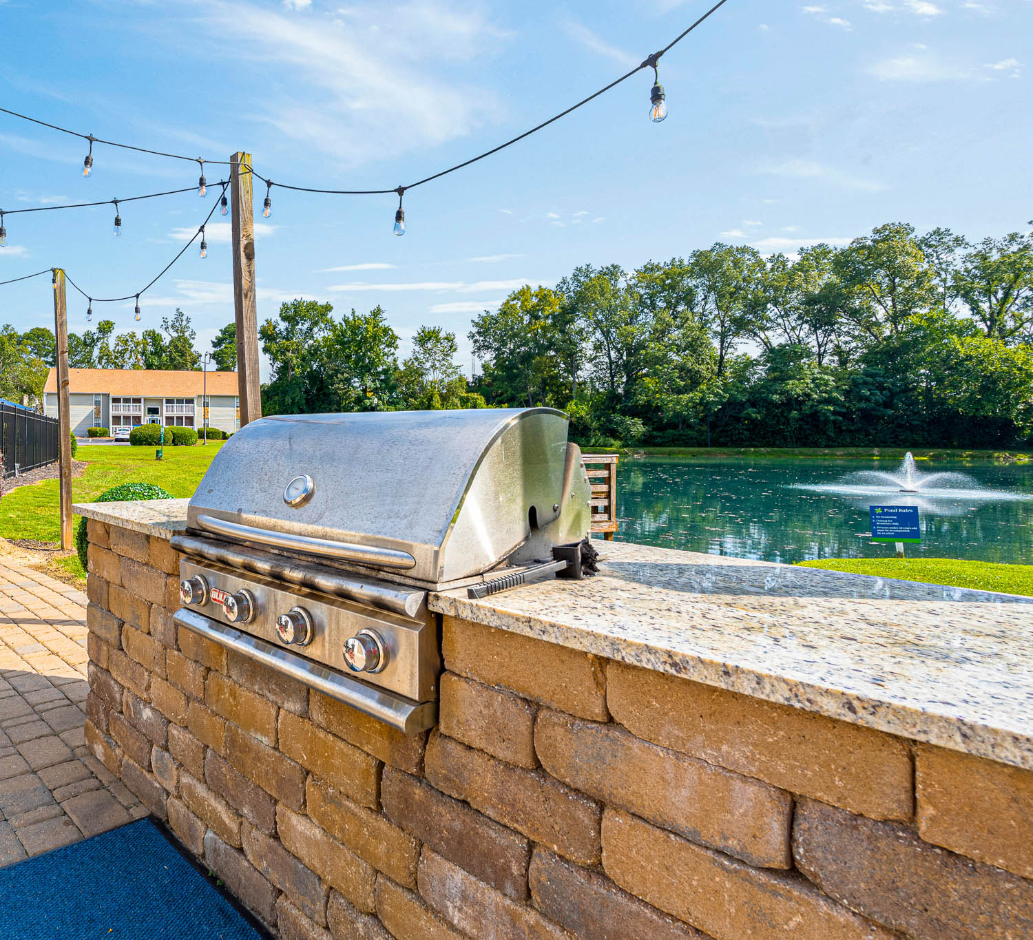 A BBQ grill is on a brick wall next to a body of water.