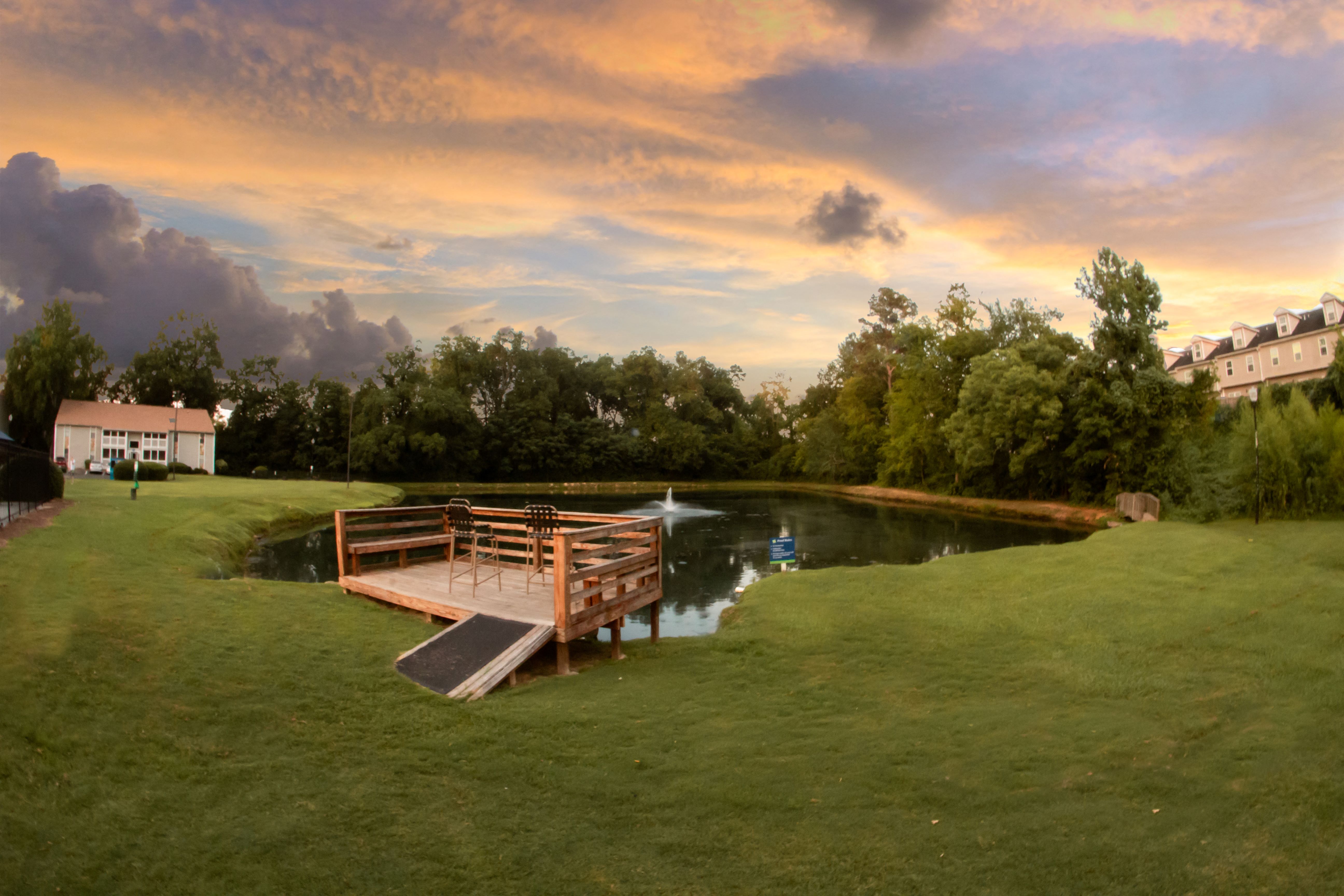 a wooden bridge over a pond at sunset