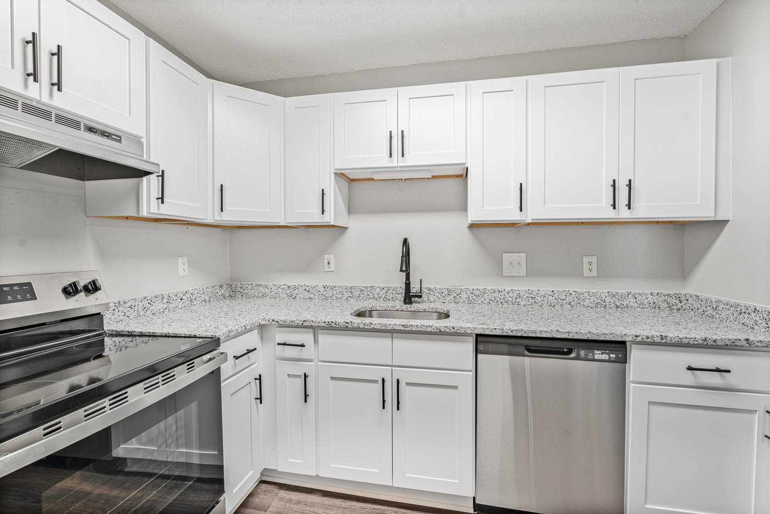 A kitchen with white cabinets and granite countertops.