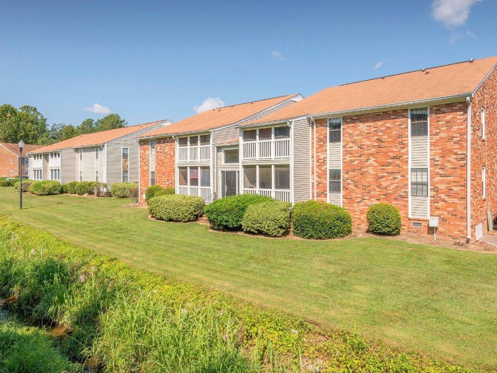 a row of brick apartment buildings with a green lawn