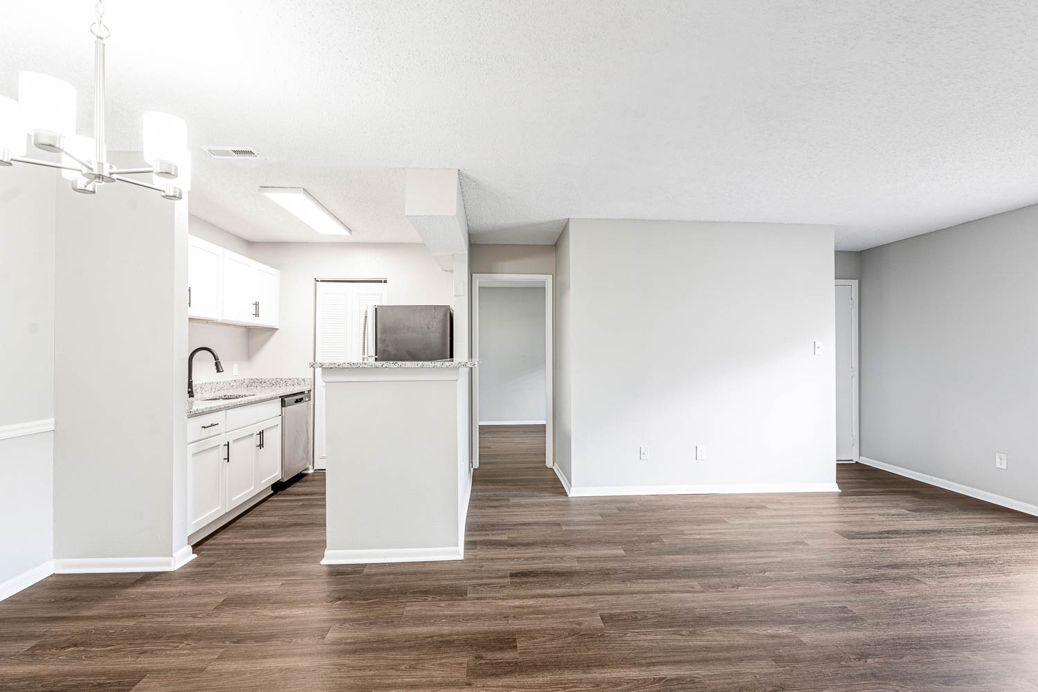 A kitchen with white cabinets and a wooden floor.