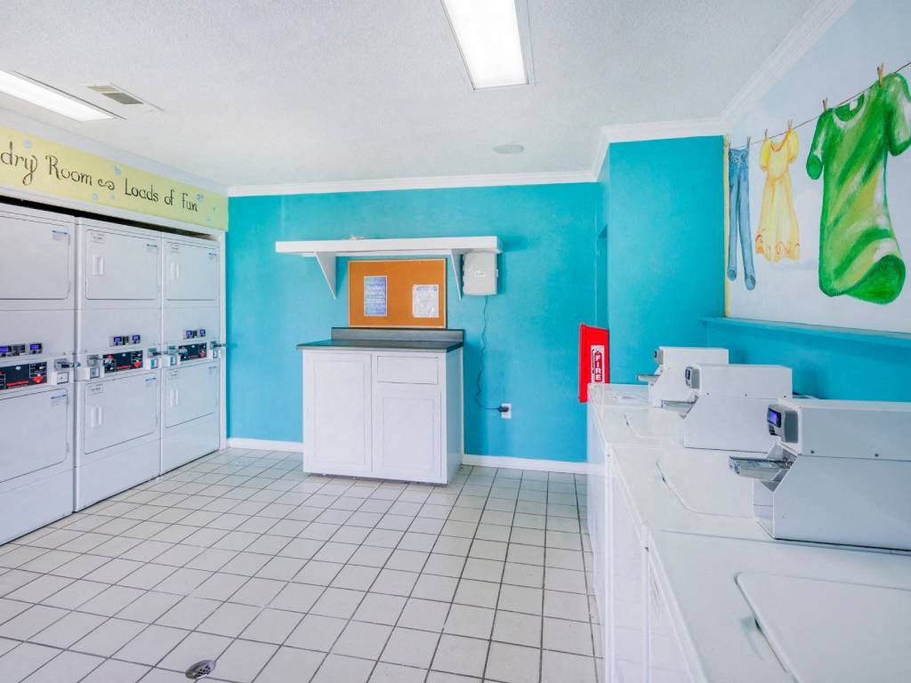 a laundry room with a tiled floor and white cabinets